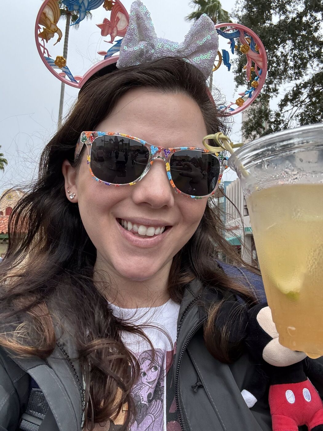 Elainea in sparkly Minnie ears holding a drink at Disney