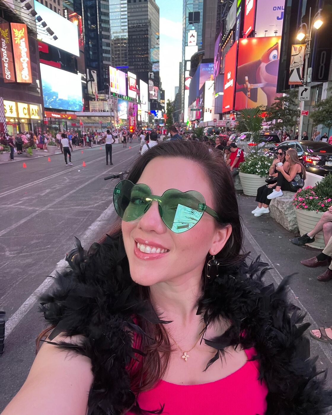 Elainea in heart-shaped sunglasses and a feather boa in Times Square