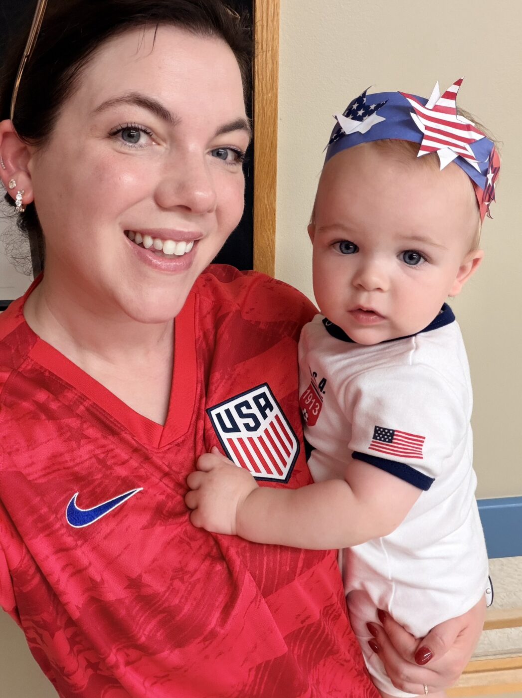Elainea holding her son, both dressed in patriotic red-white-and-blue