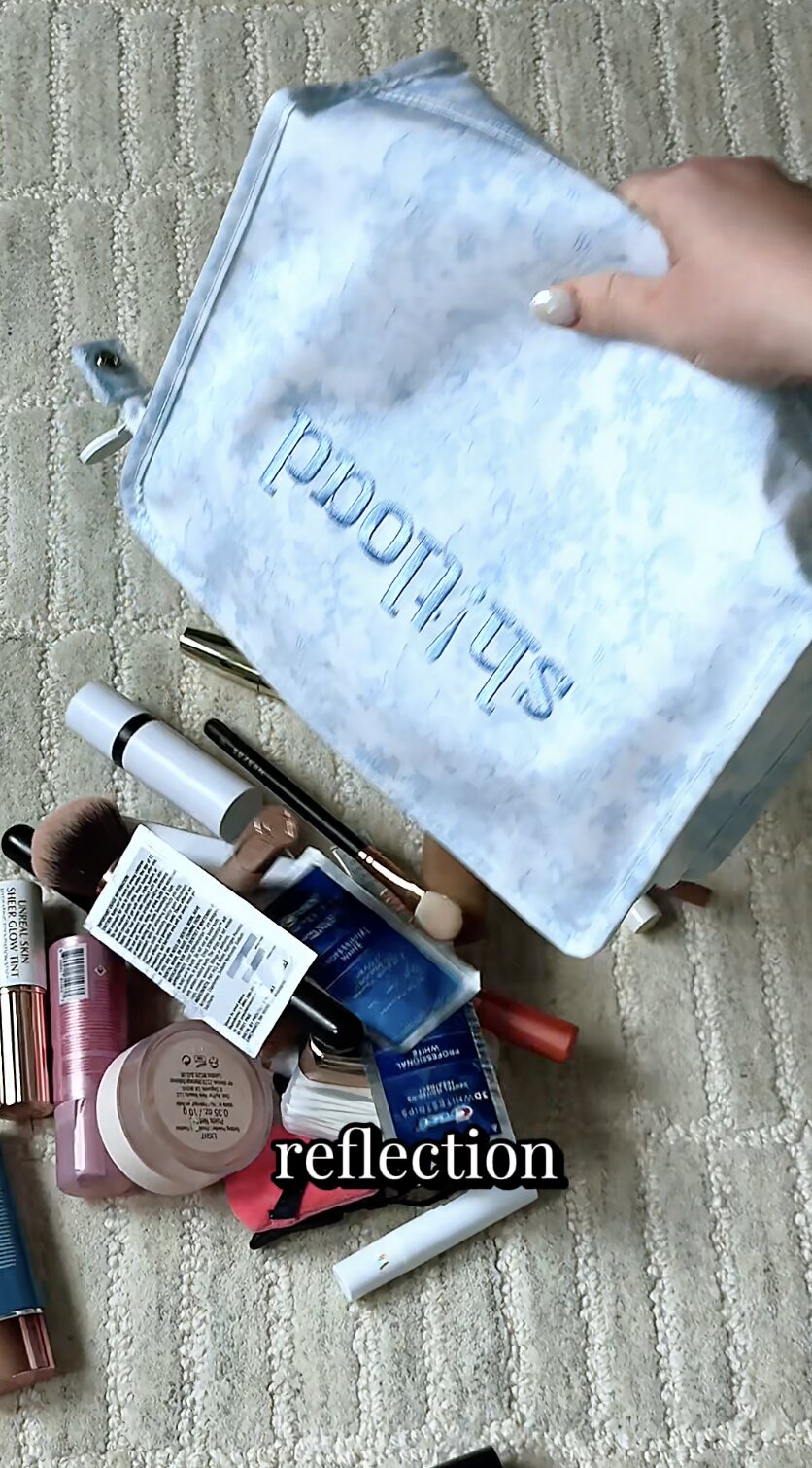 Reflection — makeup bag spilled open with products scattered on a rug
